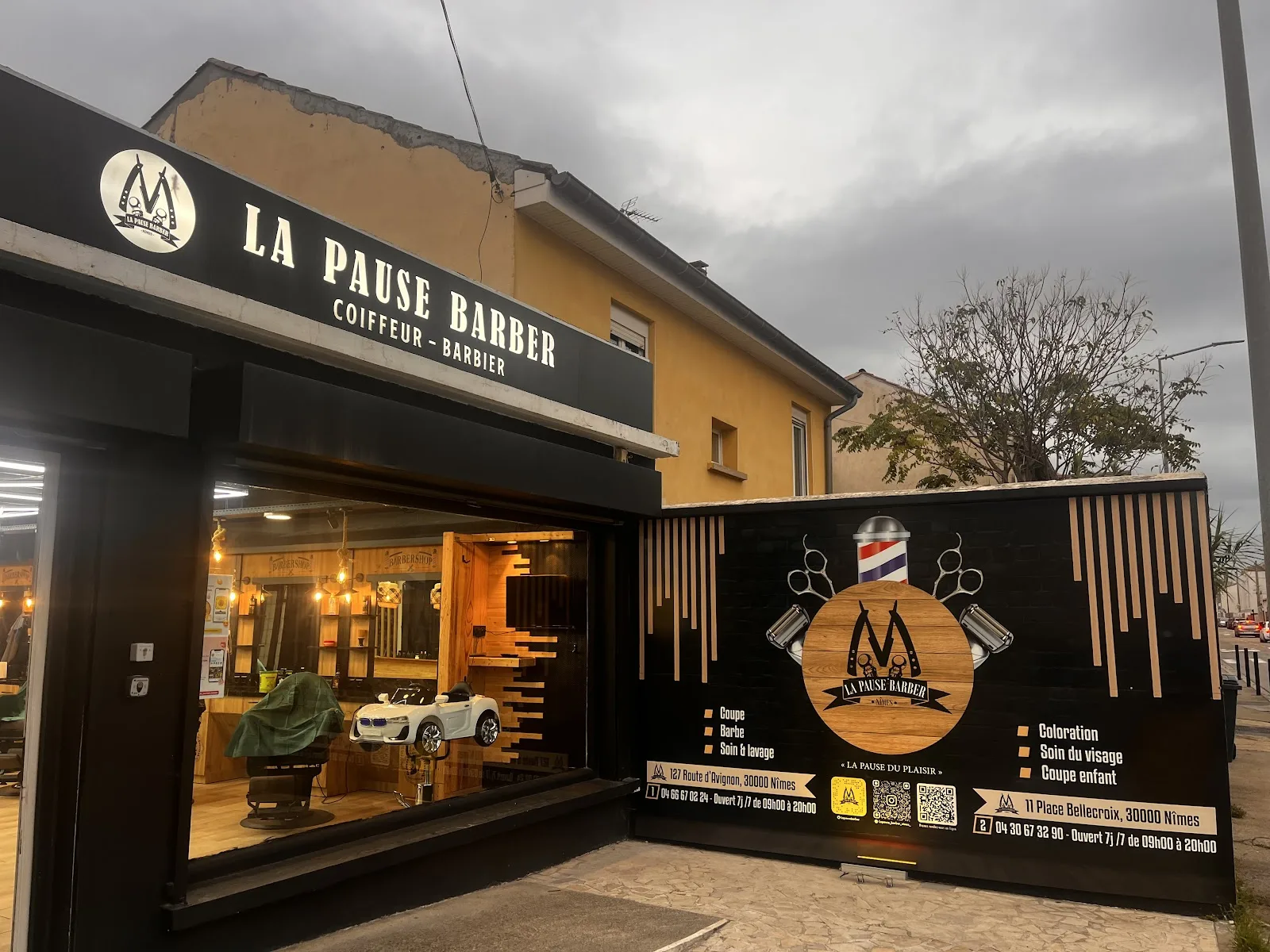 La devanture éclairée de La Pause Barber, coiffeur barbier route d'Avignon à Nîmes, enseigne lumineuse et vitrine allumée