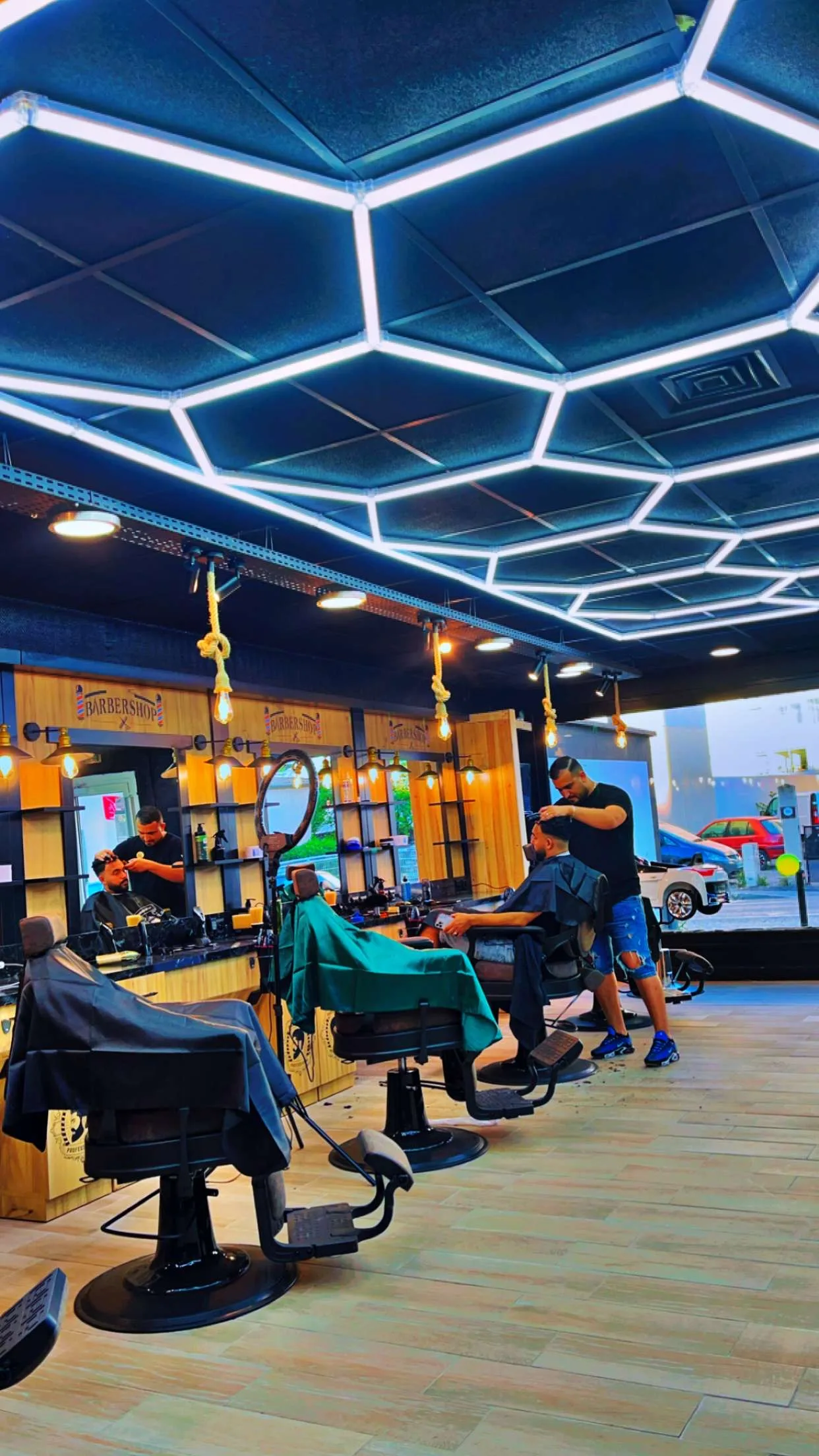 Le plafond en lignes lumineuses hexagonales posé par OH Elec chez La Pause Barber à Nîmes, au-dessus des fauteuils de barbier